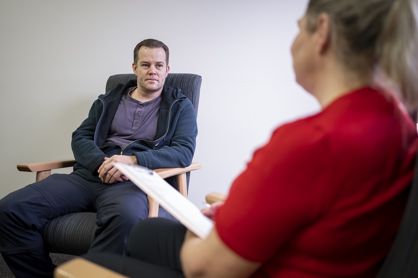 Therapist talking to a male middle aged patient sitting on a chair 