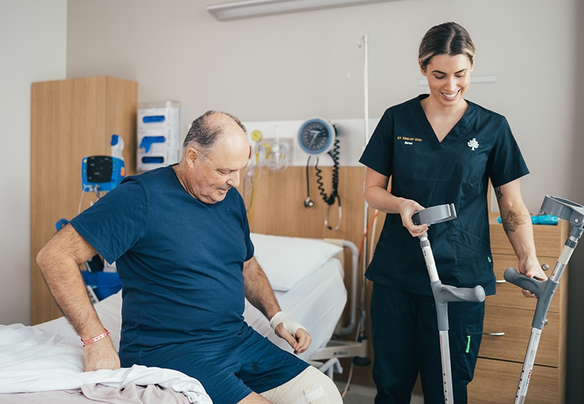 A caregiver helps an orthopaedic surgery patient with his crutches 