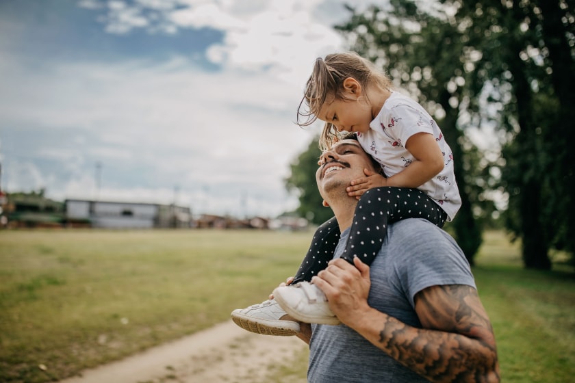 Young father outdoors with child on shoulders