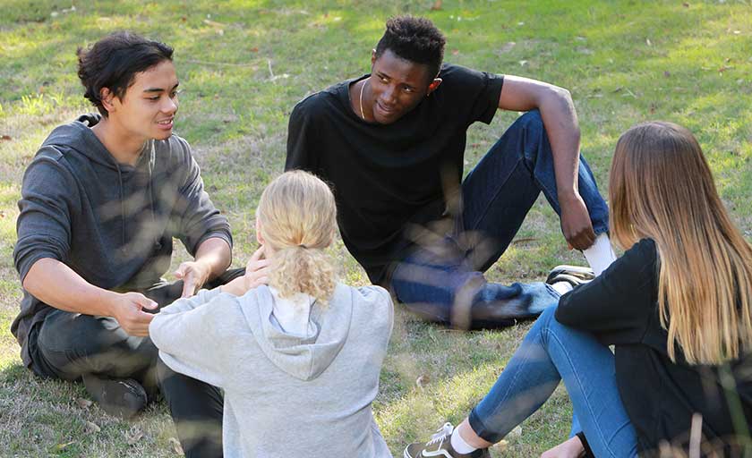 Group of four youth sitting on grass