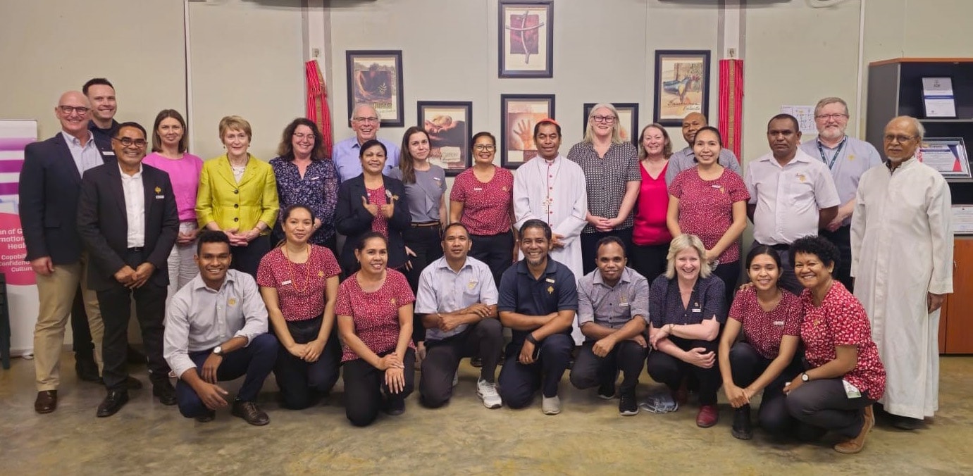 Caregivers standing and crouching in a room looking at the camera.