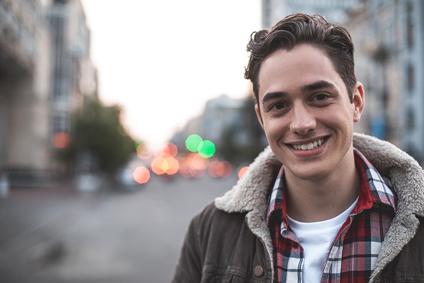 A smiling young man on a city street.