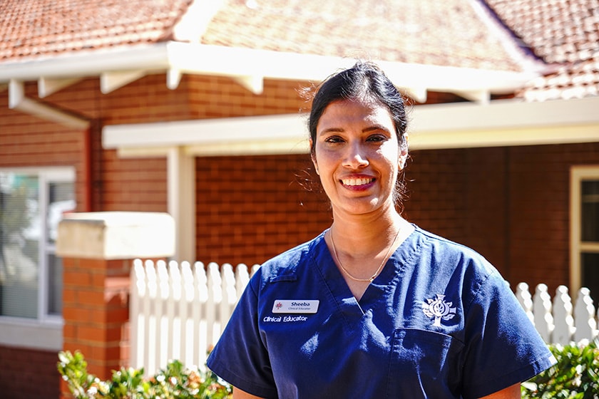 A St John of God Health Care caregiver smiles in medical scrubs