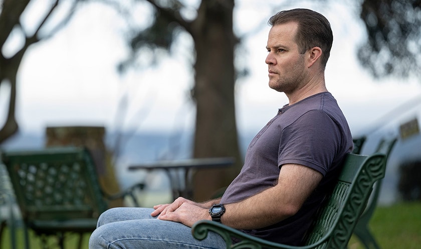 A man sits on a park bench deep in thought