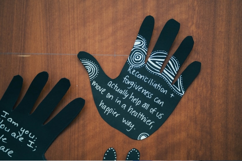 Shape of hands cut out of paper with words on reconciliation written on them