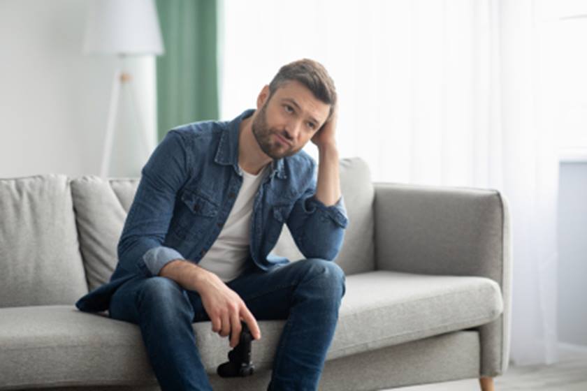 Man sitting on couch leaning head in his hand