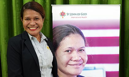 Angela Pinto with her picture on the St John of God International Health banner