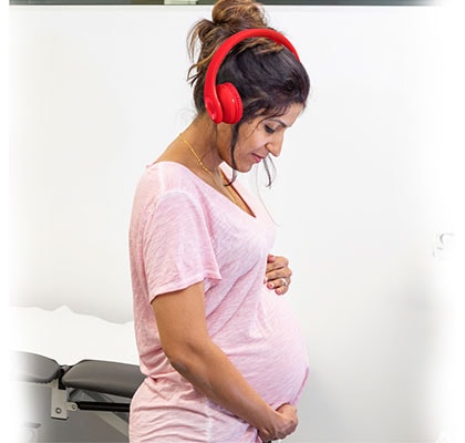 maternity patient listing to playlist with red headphones
