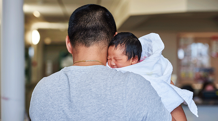 Dad holding baby tenderly over shoulder