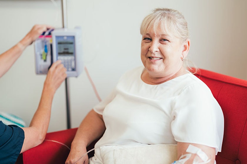 Healthcare at Home Infusions - Patient seated on armchair with caregiver attaching IV