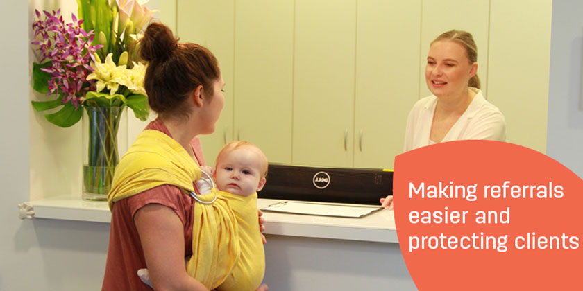 Making referrals easier and protecting clients banner including caregiver liaising over the counter top with a patient who is wearing a baby in a wrap