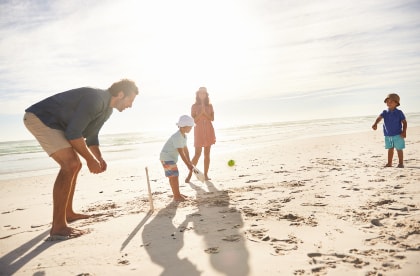 Family playing cricket on beach