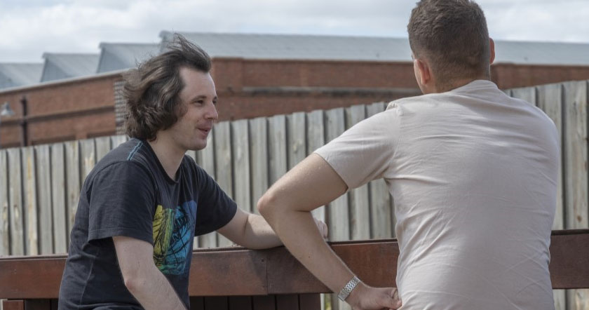 Two people sit outside talking.
