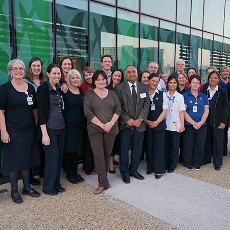 Large group of caregivers pose for photograph in front of the Cancer Centre