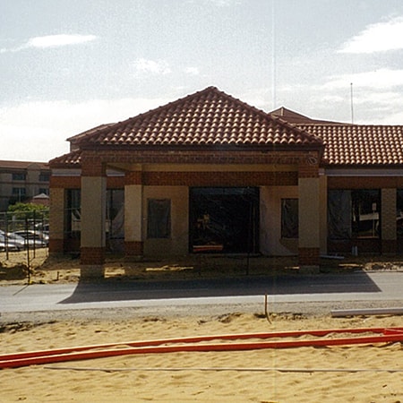 Exterior photograph of the Murdoch Surgicentre under construction with a yellow sand and a newly laid road in foreground