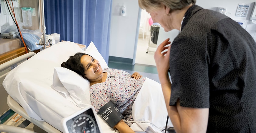 Pregnant woman having blood pressure measured by caregiver