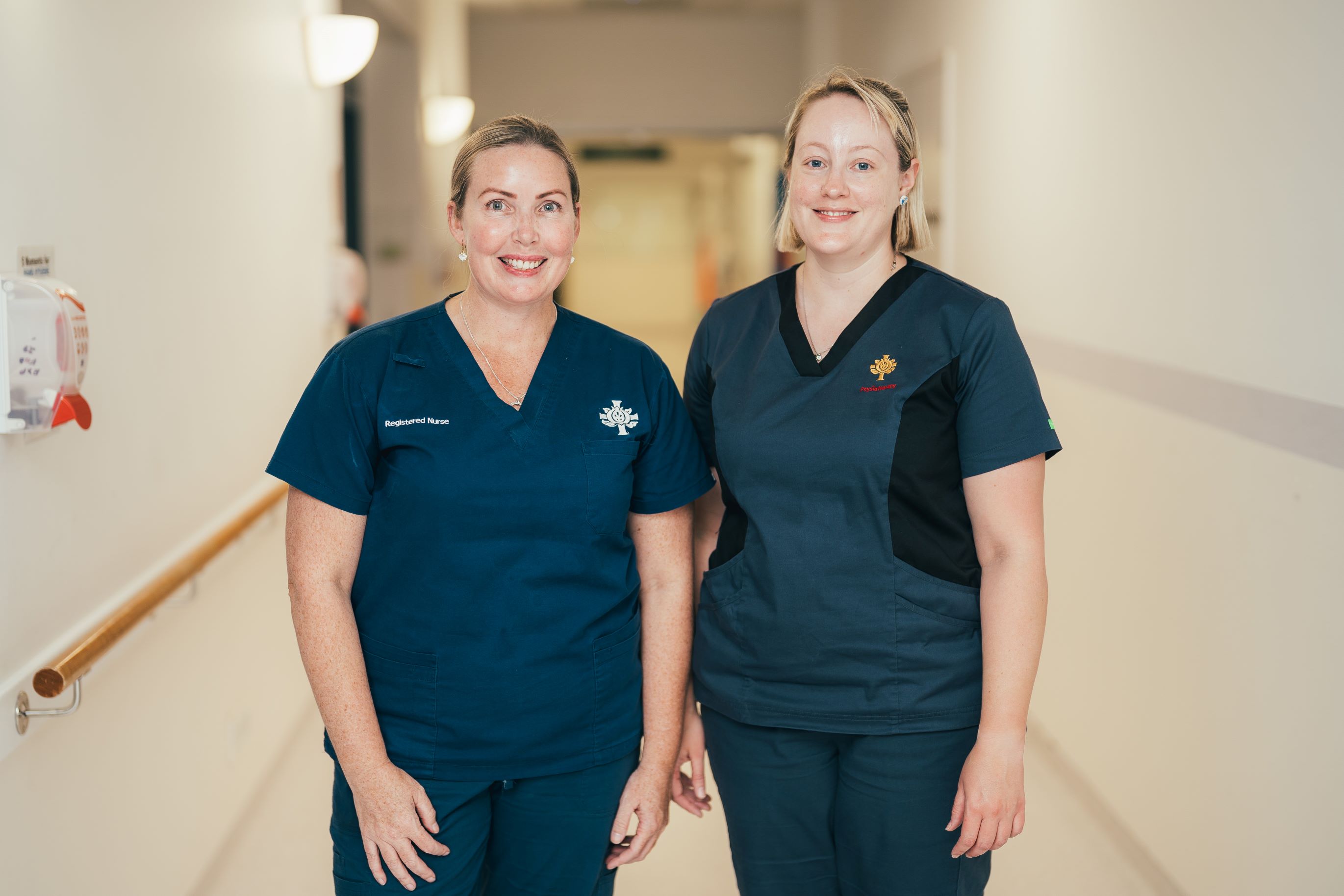 A nurse and physiotherapist in scrubs in a hospital corridor