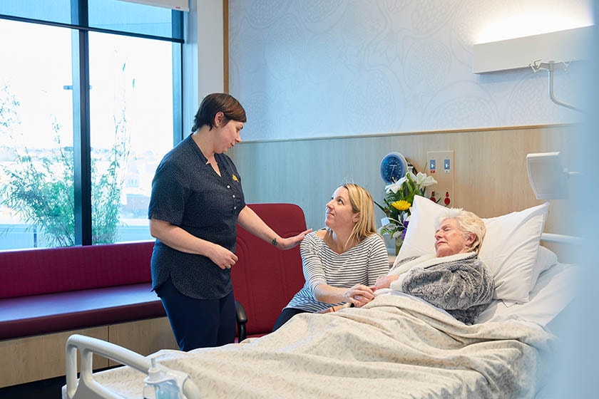 Caregiver with patient and visitor in room.