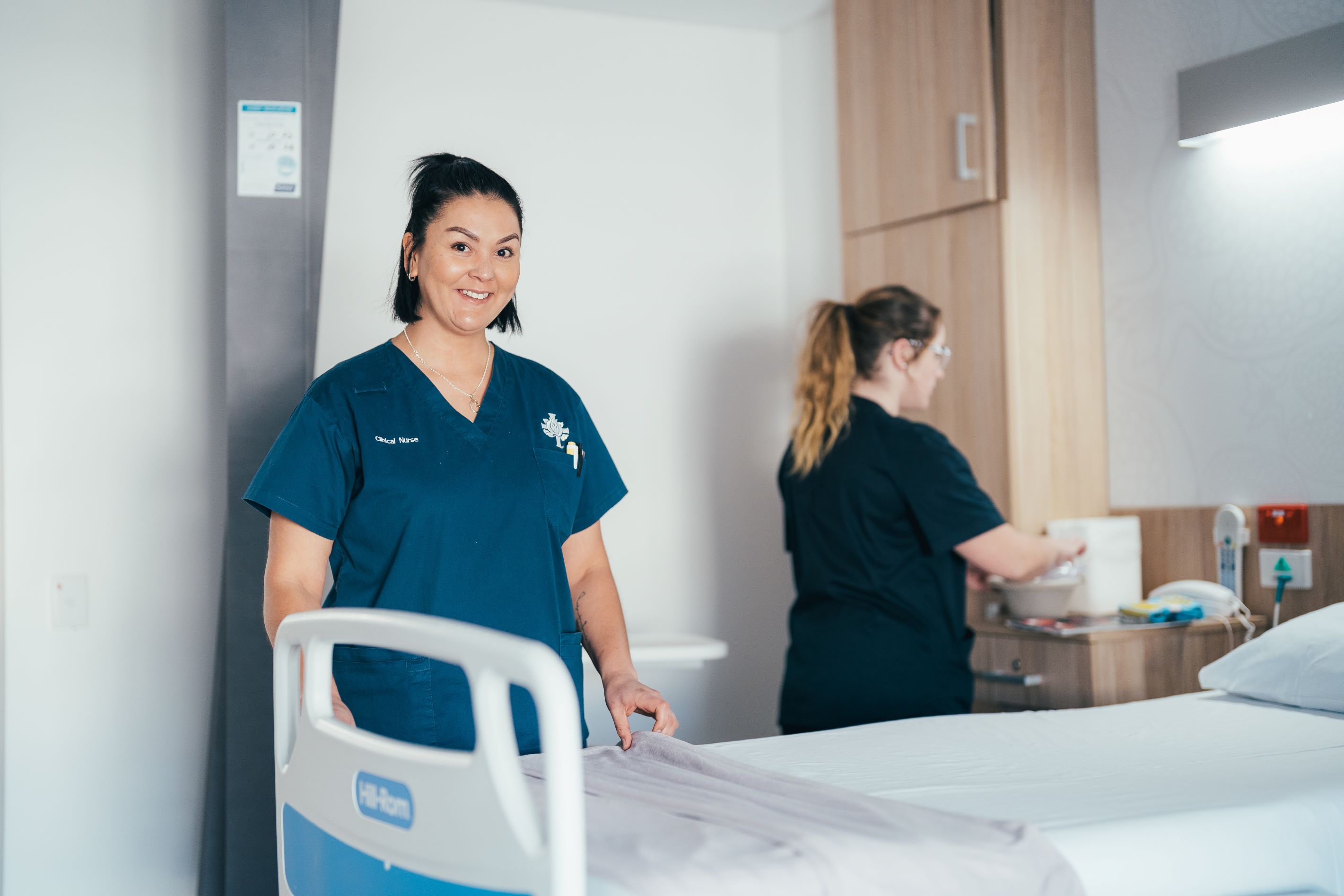 Caregiver standing next to hospital bed smiling