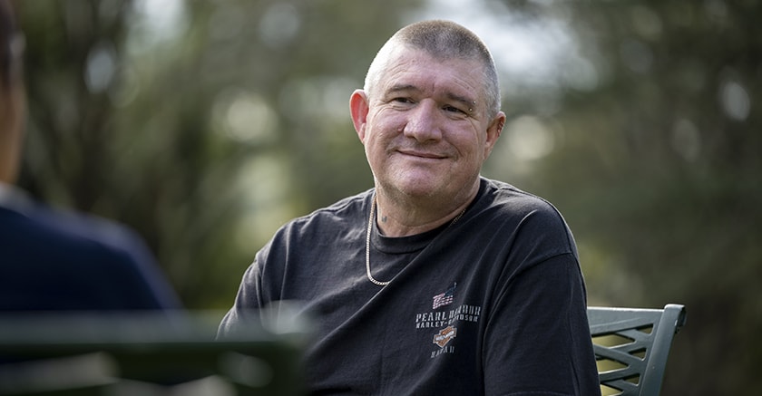 Mental health client smiling while sitting in gardens at St John of God Richmond Hospital