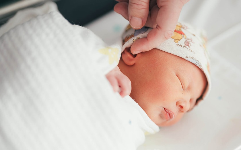 A finger brushes across the head of a sleeping new born.