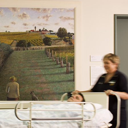 patient getting moved in bed with artwork behind and main focus 