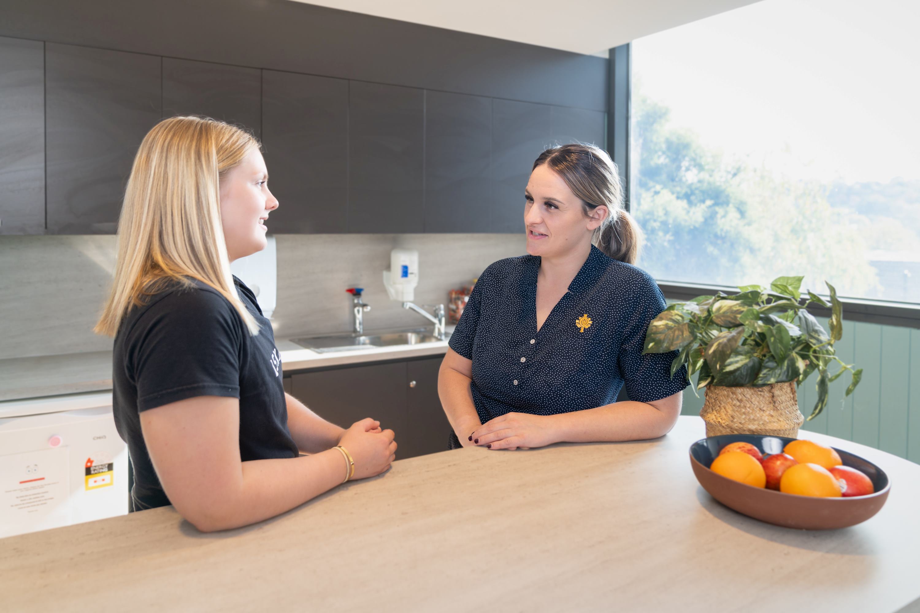 Caregiver and client together in kitchen talking