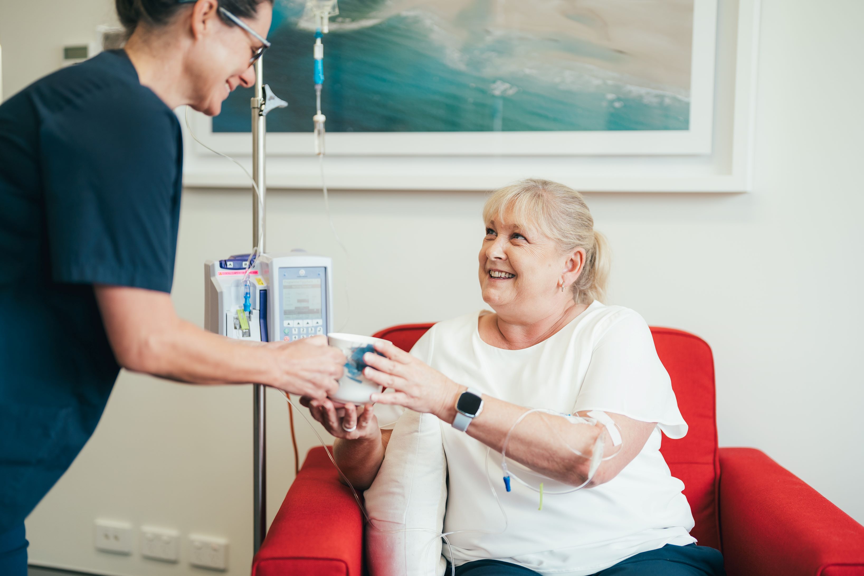 Caregiver bringing patient a cup of tea during her infusion