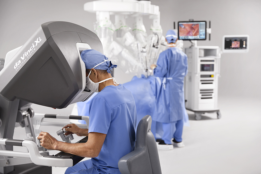 Image of medical doctor in scrubs using da Vinci Xi to undertake surgery.