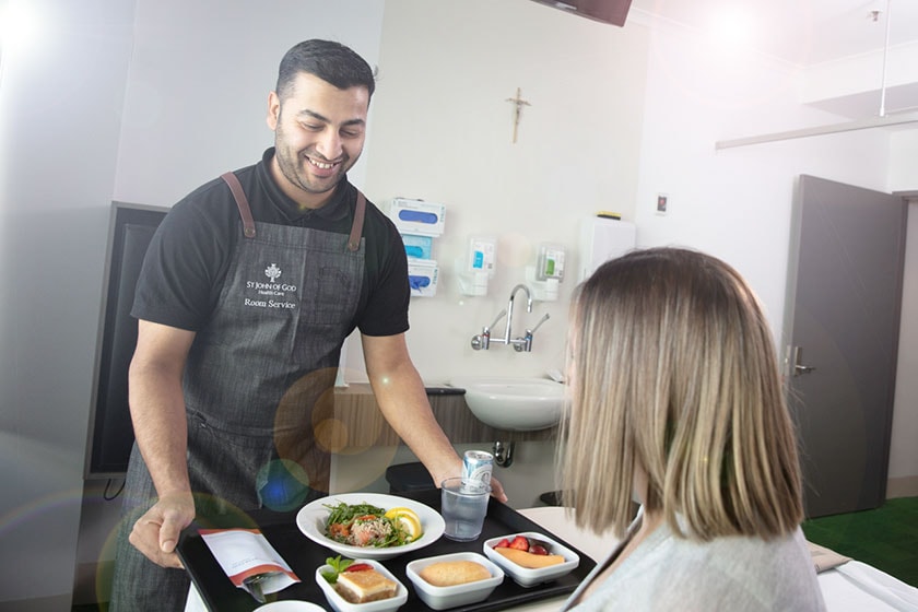 Caregiver serving a patient's room service order