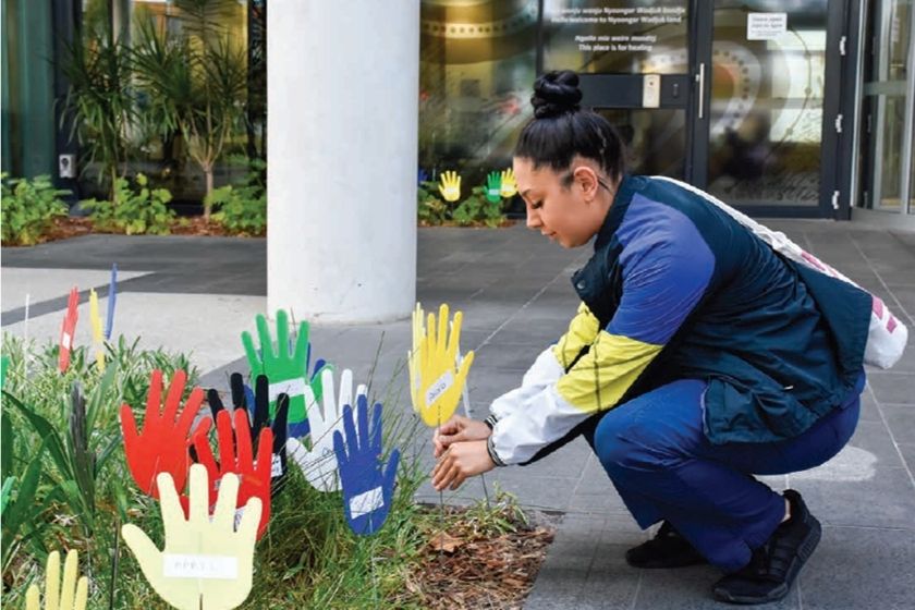 Image of caregiver kneeling down planting a hand for the RAP