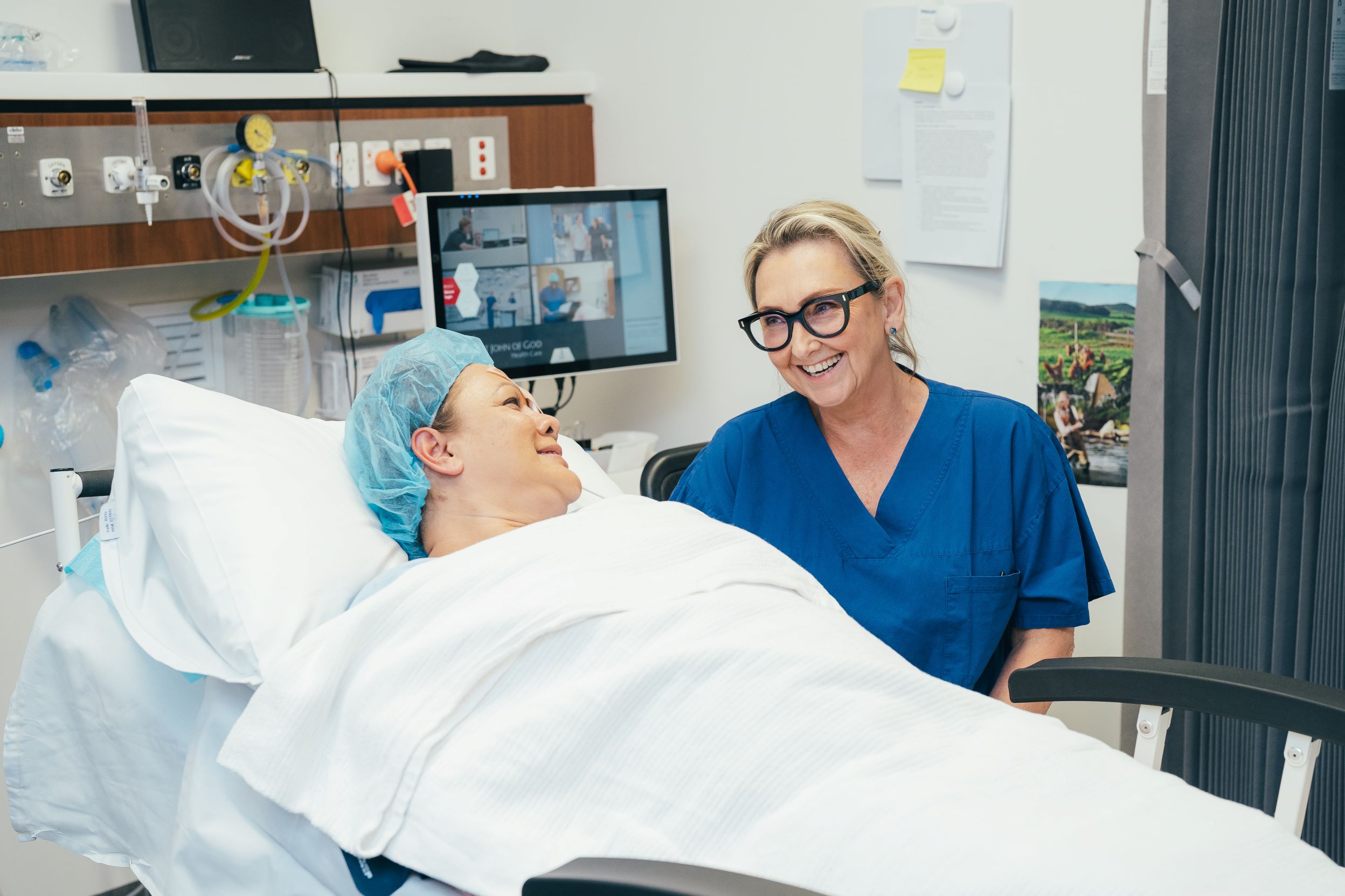 Patient in hospital bed after operation speaking with caregiver