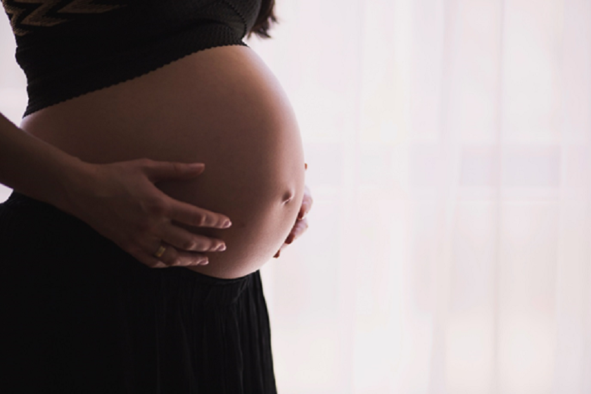 Mid shot of pregnant person holding belly