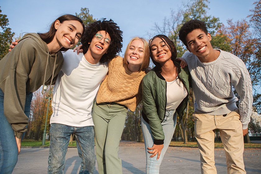 Five young adults smile for a photo.