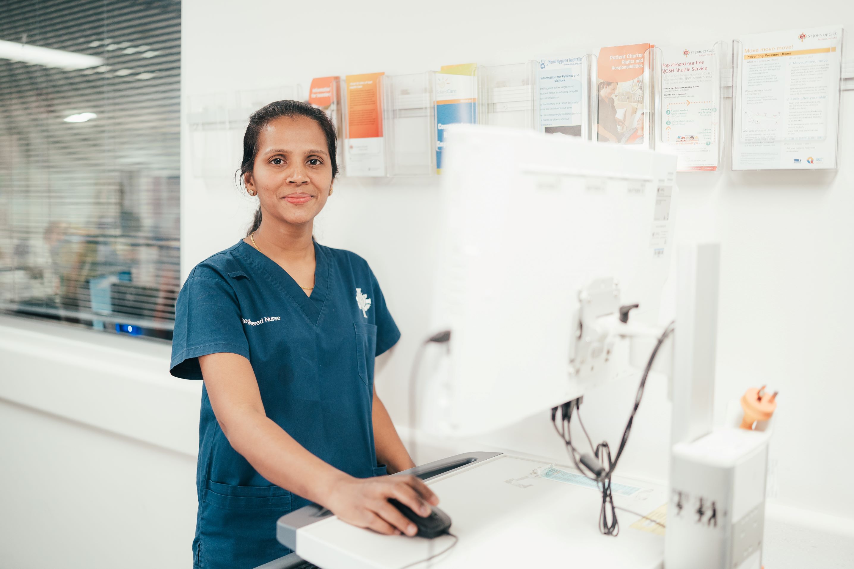 Caregiver standing at hospital computer monitor