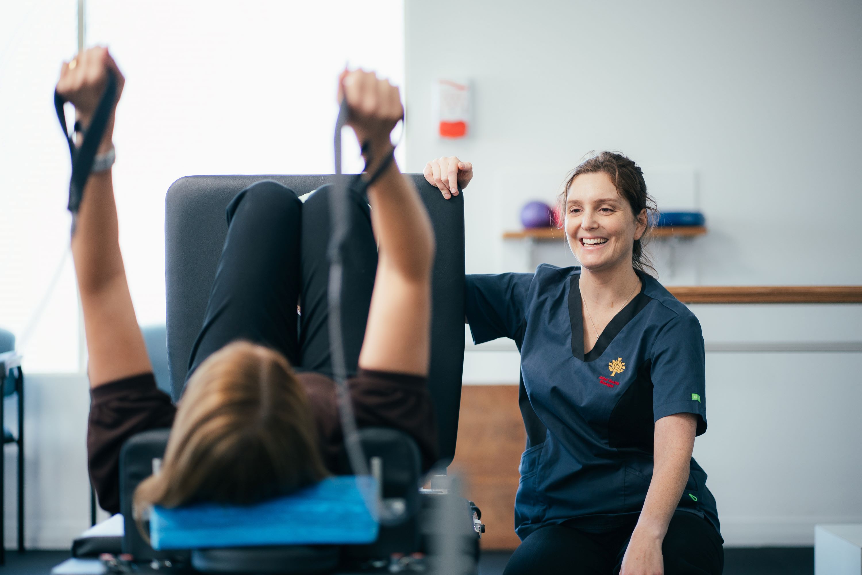 Caregiver supporting patient on excercise equipment