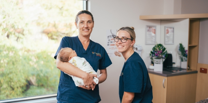 Two midwifes holding a newborn baby