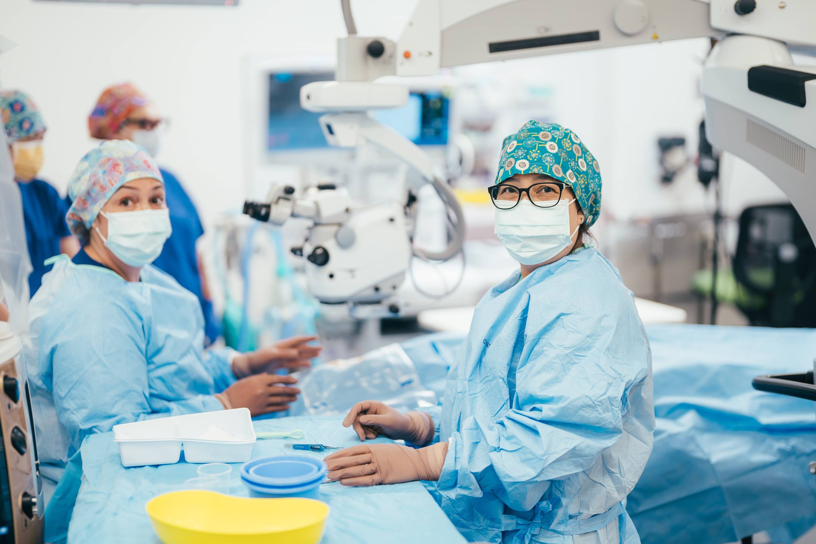 Two caregivers in operating room with scrubs, gloves and masks on