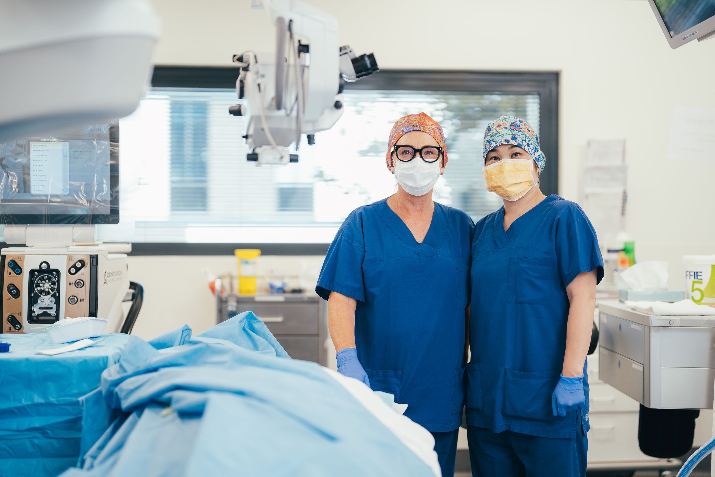 Two caregivers with masks and gloves in operating theatre