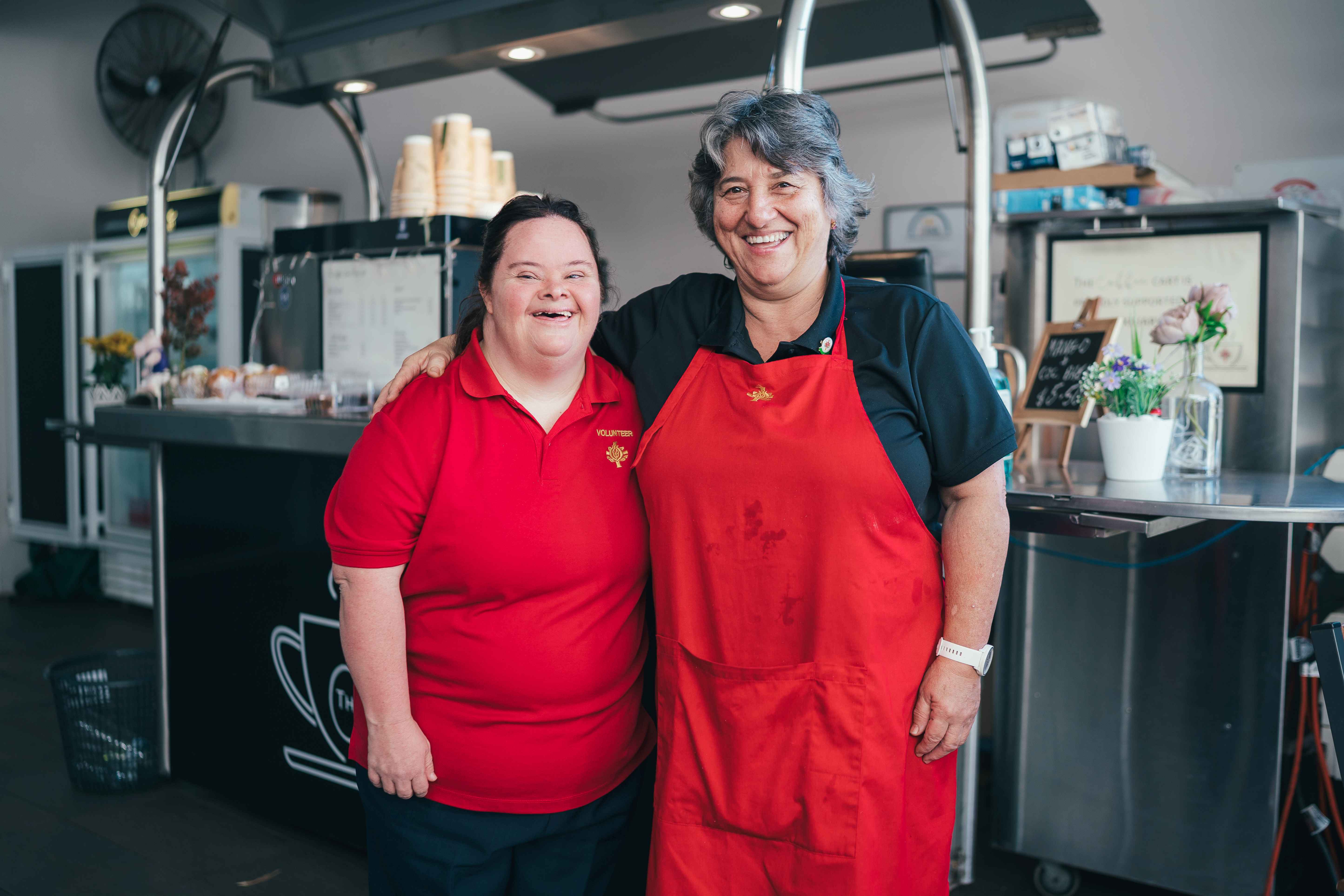 Two caregivers standing in hospital kitchen smiling