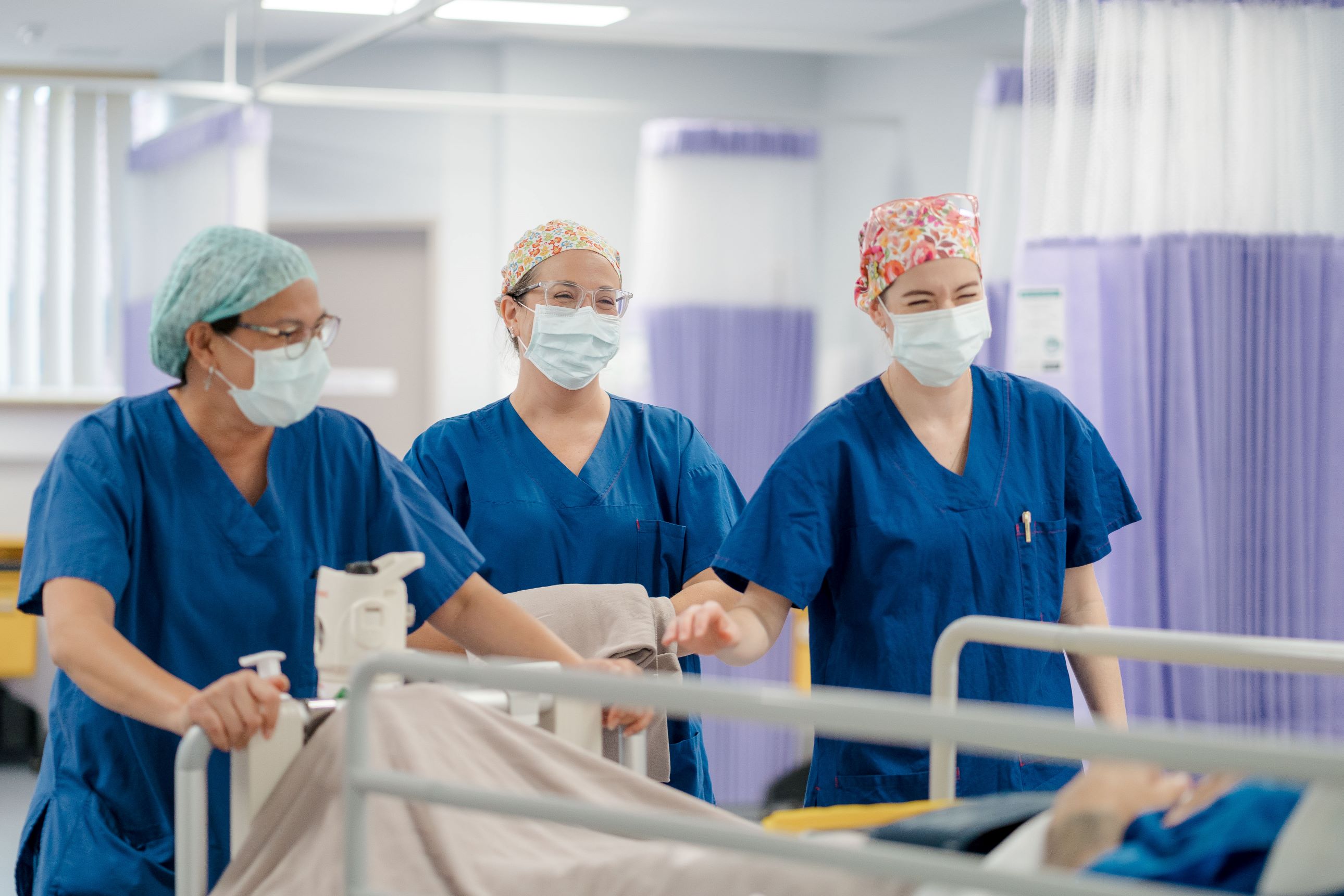 Three caregivers transporting a patient in bed in the hospital