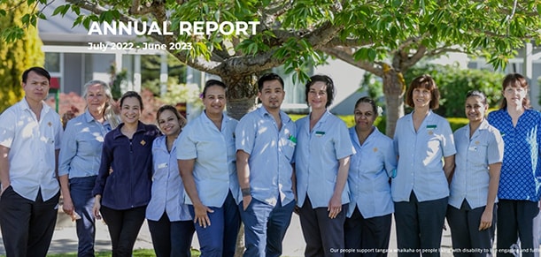 A row of St John of God Hauora Trust caregivers standing outside in a park.