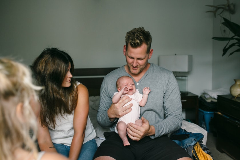 Young family sitting on couch\ with father holding newborn