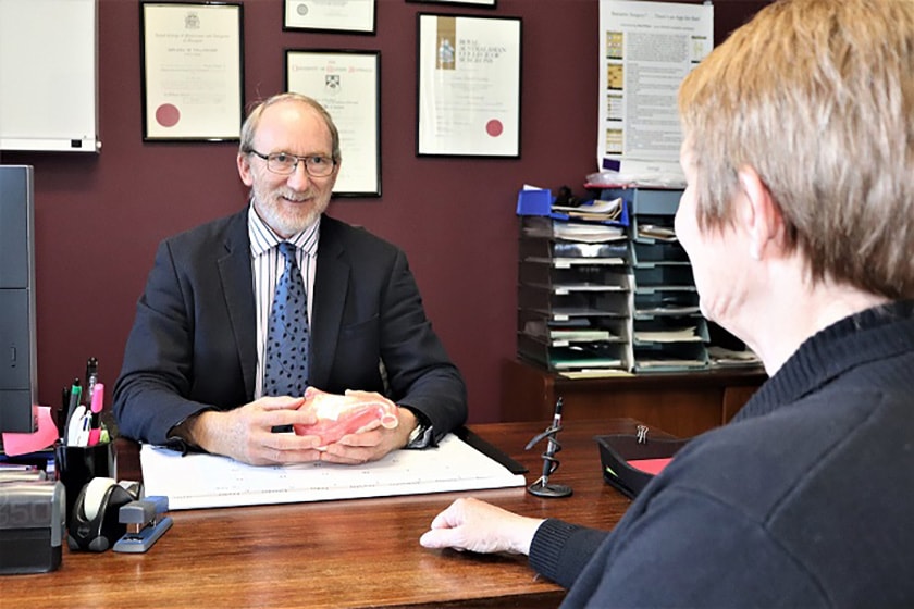 Specialist liaising with patient in an office face-to-face at a desk