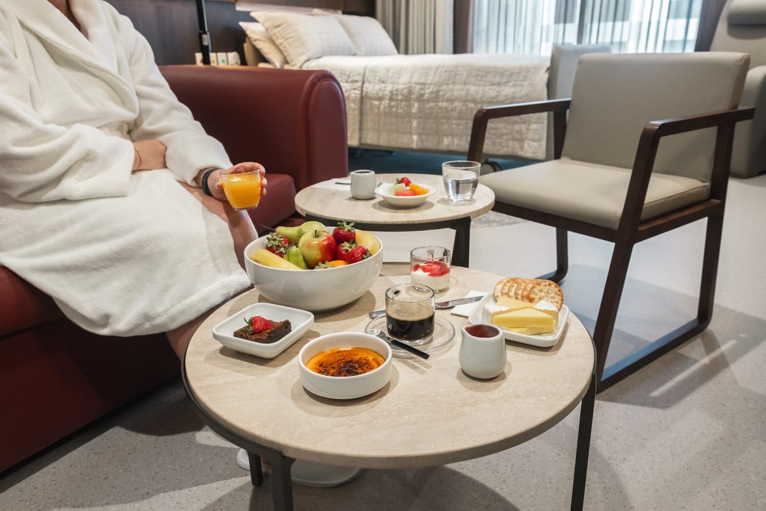 A patient sits in a robe and enjoys a room service meal in The Suites
