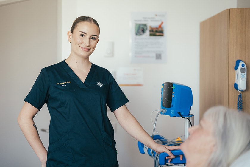 A nurse stands next to the bedside of a patient