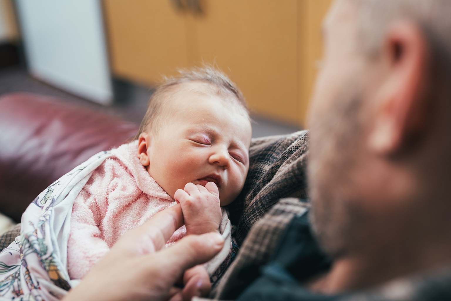 A dad looks on his newborn baby