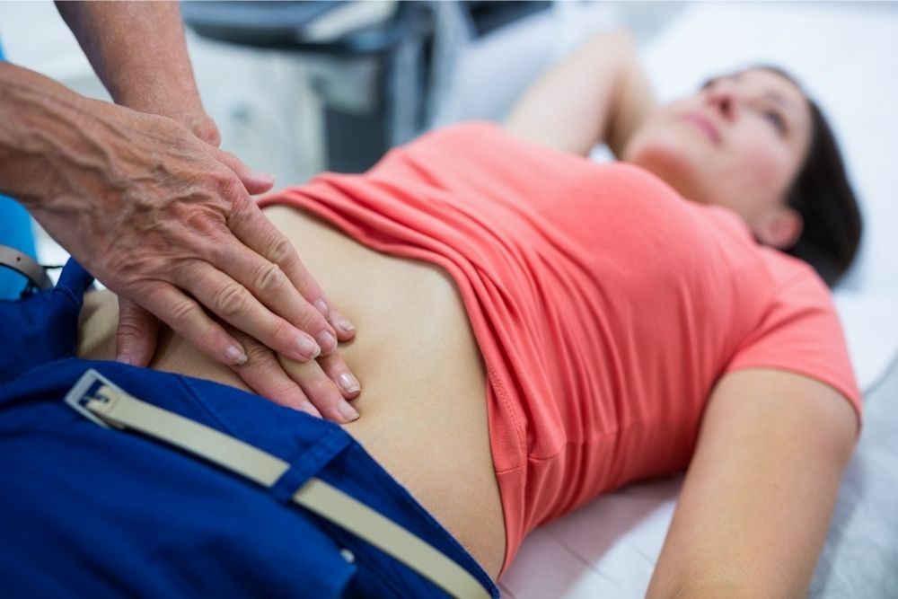 A medical professional with their hands on a patients stomach