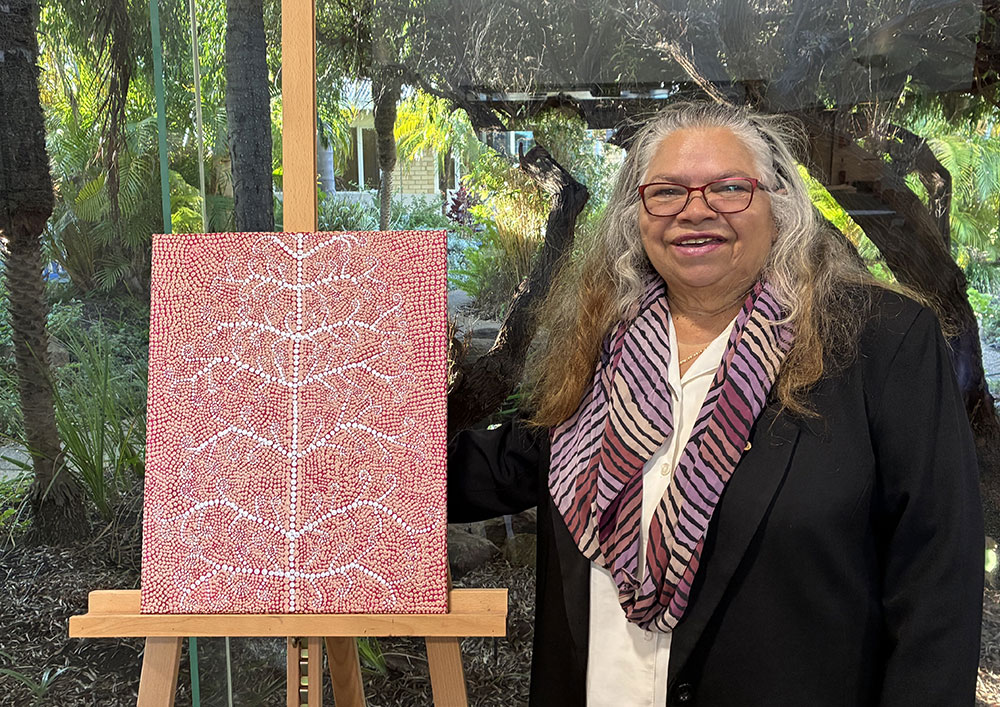 Carol Martin OAM standing with one of her artworks displayed at St John of God Geraldton Hospital