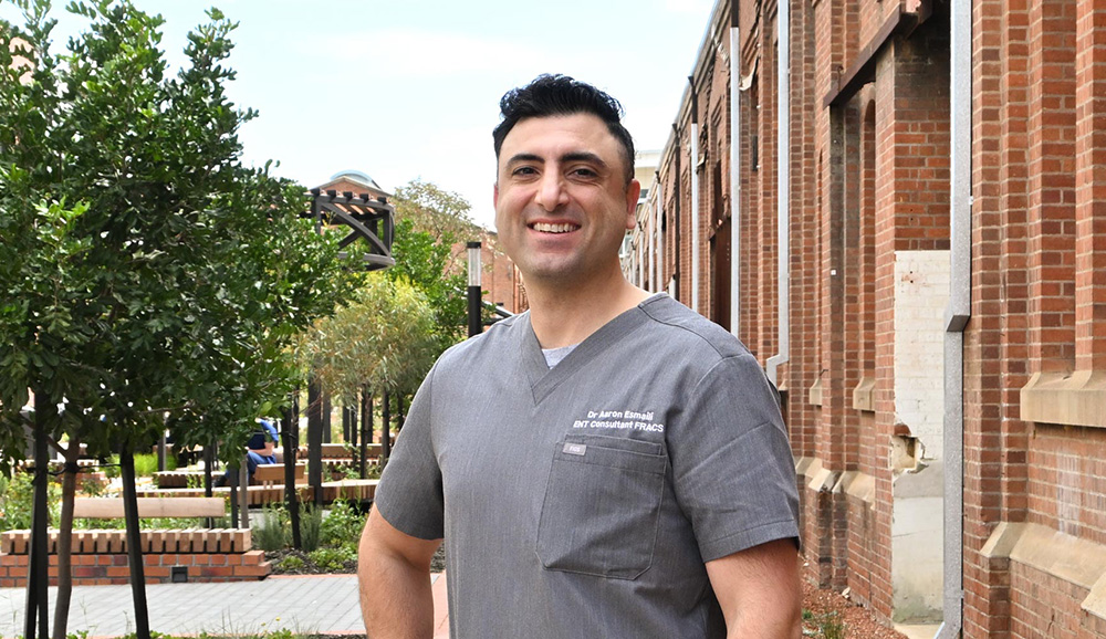 A smiling Dr Aaron Esmaili stands outside St John of God Midland Private Hospital